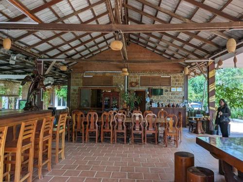 贡布Kampheak Roath Bungalows的餐厅设有酒吧,配有木桌和椅子
