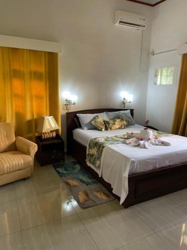 马埃岛贝拉扎尔区兰花日落旅馆的一间卧室配有一张床、一把椅子和一张沙发