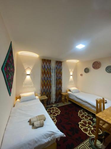 希瓦Naqqosh的酒店客房设有两张床和一张桌子。