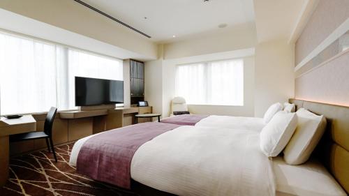 东京remm plus Ginza的酒店客房配有一张床、一张书桌和一台电视。