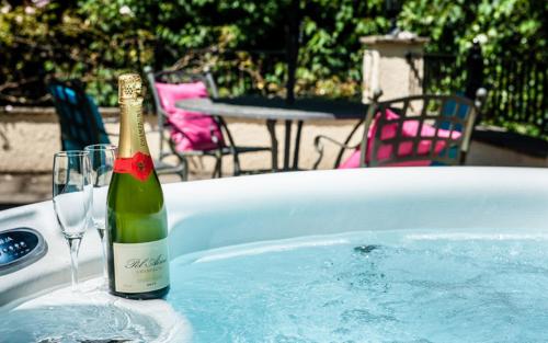 UplymeAcorns with own hot tub, romantic escape, close to Lyme Regis的一瓶香槟和浴缸内的一杯