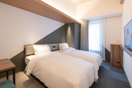 那霸Prince Smart Inn Naha的一间酒店客房,设有两张床和电视