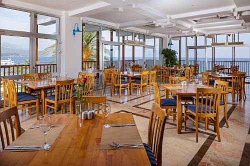 凯麦尔AQI Hydros Club的餐厅设有木桌、椅子和窗户。