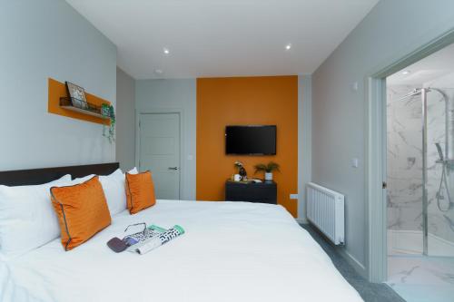 普里茅斯Apartment Three - Free Private Car Park - sleeps 6 - 3 shower rooms - by Ocean City Retreats的一间卧室配有一张白色的床和橙色的墙壁