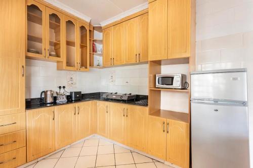 纳库鲁North Manor Nakuru的厨房配有木制橱柜和不锈钢冰箱。