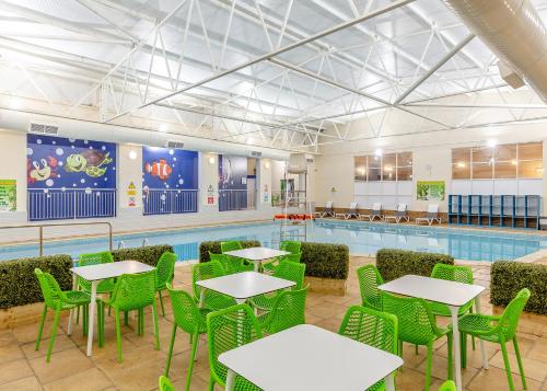 伊尔弗勒科姆North Devon Resort的一个带桌椅的泳池间和一个游泳池