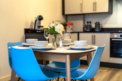 斯坦斯Ashview 2 - Heathrow - Thorpe Park - Free Parking的一张带蓝色椅子和鲜花的餐桌