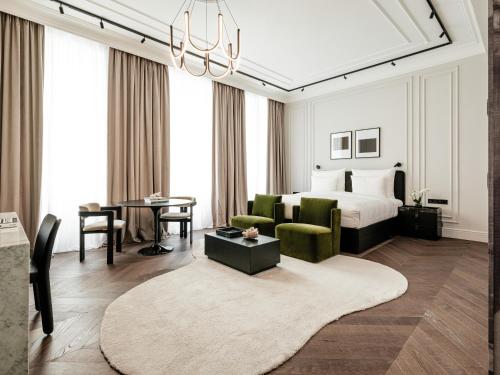 维也纳The Amauris Vienna - Relais & Châteaux的一间卧室配有一张床,客厅配有桌子