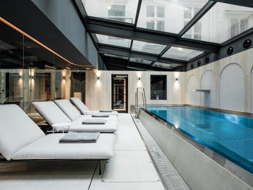 维也纳The Amauris Vienna - Relais & Châteaux的一个带白色椅子的室内游泳池和游泳池