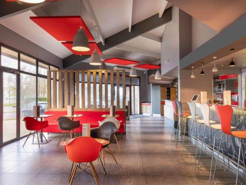 阿姆博斯昂布瓦斯宜必思酒店的餐厅设有红色的桌椅和窗户。