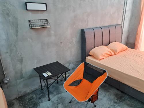 芙蓉Lot 85 Seremban Town New Cozy Homestay Lobak的一张桌子和一张床边的橙色椅子