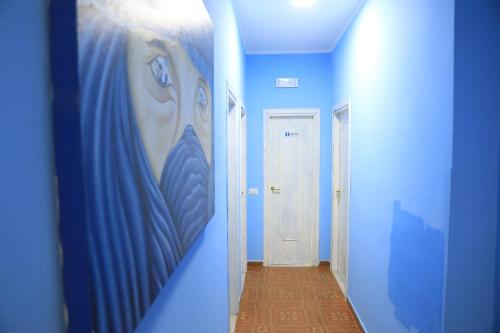 特罗佩阿First Hostel Tropea的走廊上设有蓝色的墙壁和墙上的绘画作品