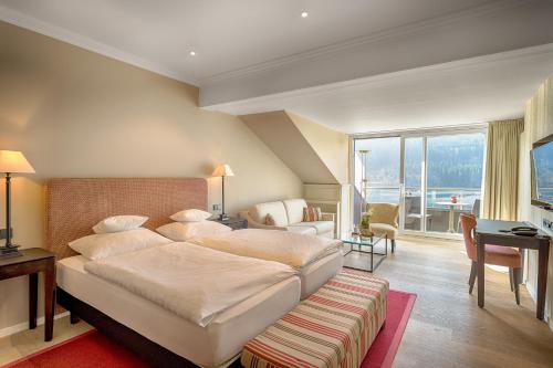 蒂蒂湖-新城Treschers Schwarzwald Hotel的一间带一张大床和一张书桌的卧室和一间房间