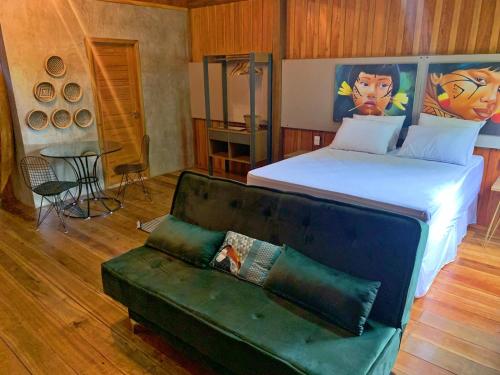 新艾朗Chalé Ubá的一间卧室配有一张床和一张绿色沙发