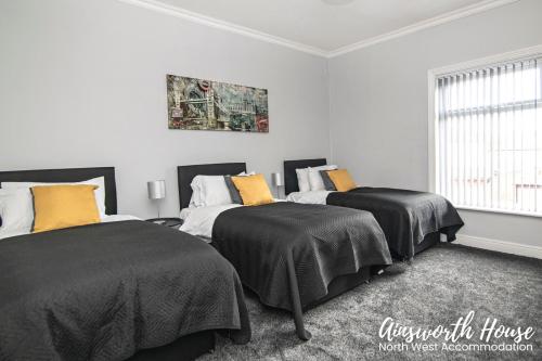 博尔顿Ainsworth House Serviced Accommodation的一间卧室配有两张带黑色和黄色枕头的床