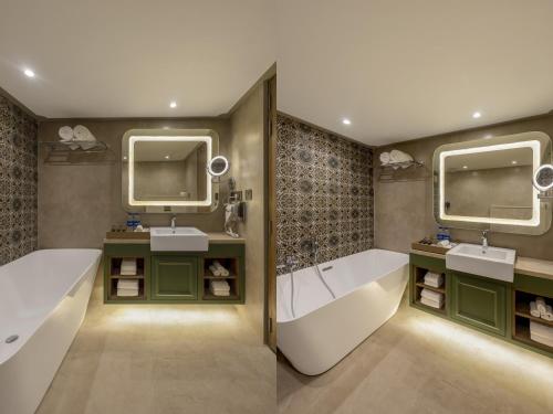斯利那加Sarovar Portico Srinagar的浴室设有2个水槽、浴缸和2面镜子