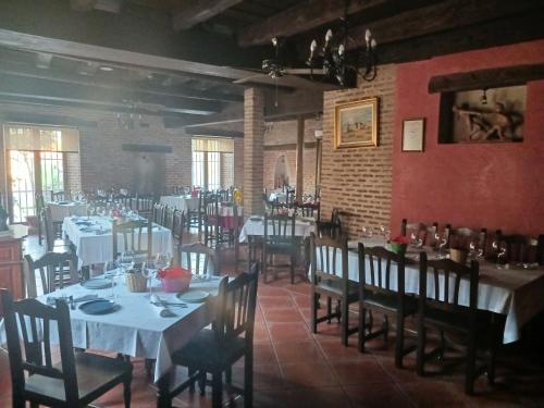 Nava del ReyHotel Restaurante Doña Elvira的一间设有白色桌椅的餐厅,拥有砖墙