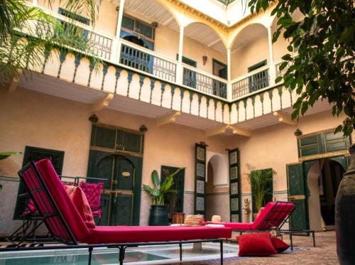 马拉喀什Riad Dar Habiba by Garden Wonders的一个带红色椅子的庭院和一个阳台