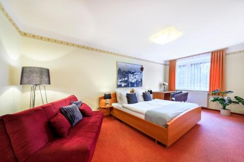 SchönbrunnSCHÖNBRUNN Hotel的酒店客房,配有一张床和一张红色的沙发