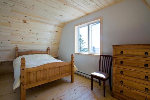 加斯佩世界尽头度假屋的一间卧室配有一张床、一个梳妆台和一扇窗户。