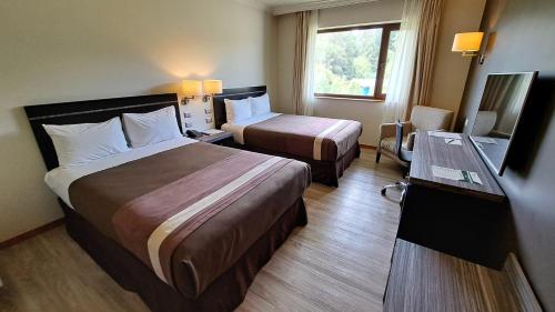 奥索尔诺Hotel Diego de Almagro Osorno的酒店客房设有两张床和一台平面电视。