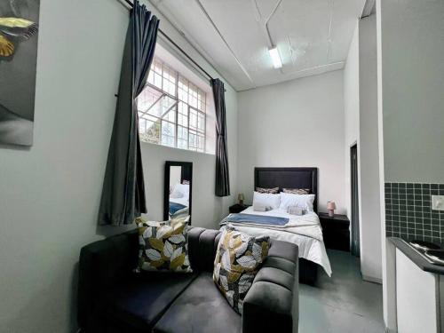 约翰内斯堡Posh Apartment next to Maboneng的一间卧室配有一张床、一张沙发和一个窗口