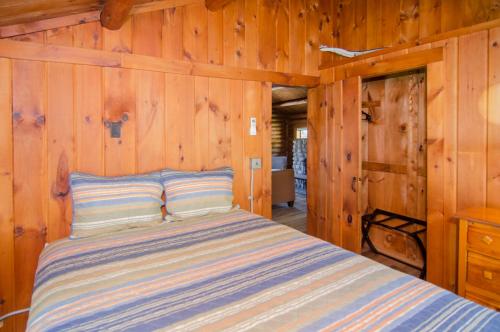 WestmoreMountain Lake Cottages的卧室配有木墙内的一张床