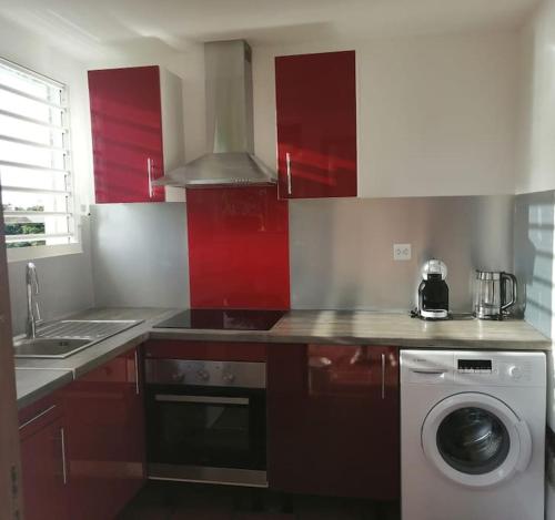 波尔兰特Duplex Rose Porcelaine - Vue Mer- Malendure的一间带红色橱柜和洗衣机的厨房