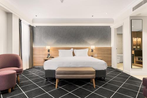 悉尼达令港假日酒店的一间卧室配有一张大床和两把椅子