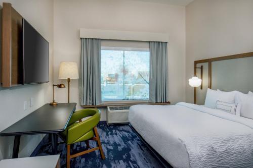 McPhersonFairfield Inn & Suites by Marriott McPherson的配有一张床、一张书桌和一扇窗户的酒店客房