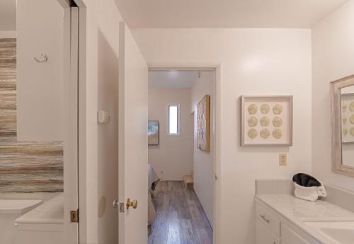 卡梅尔3797 Pine Place apts的浴室设有白色的墙壁和带水槽的走廊