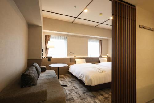 神户SK HOTEL Kobe Ekimae的酒店客房,配有床和沙发