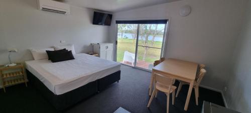 NarangbaNarangba Motel (formerly Brisbane North B&B and Winery)的一间卧室配有一张床、一张桌子和一个窗户。