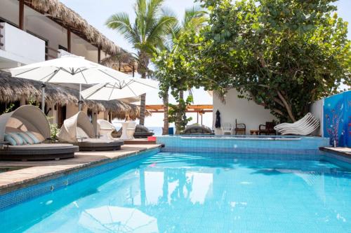 兹波利特Hotel Playa Zipolite的酒店旁的游泳池配有椅子和遮阳伞