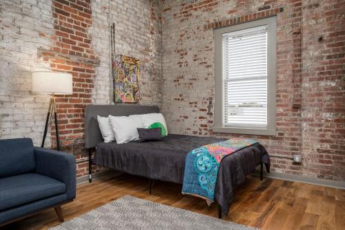 落基山The Davis Lofts at Main Street - Unit 3D的一间卧室配有一张床、一把椅子和砖墙