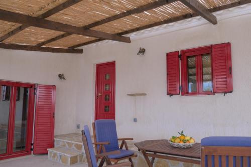 Makris GialosYasemia Wood & Stone Villa的红色窗户和桌椅的房间