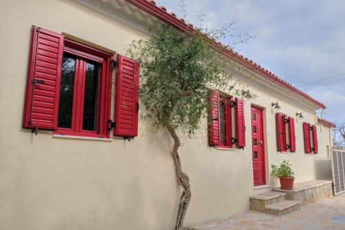 Makris GialosYasemia Wood & Stone Villa的一座有红色百叶窗和一棵树的房子