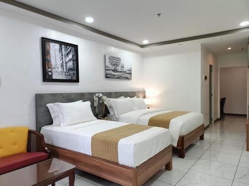 马尼拉Rosh Hotel的酒店客房,配有两张床和椅子