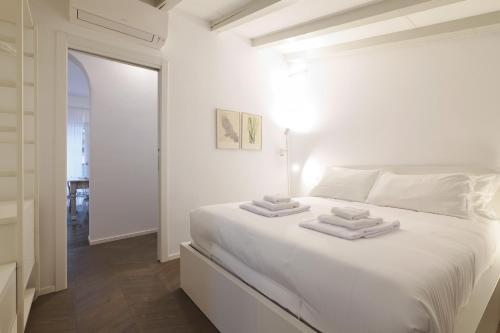 米兰PRESTIGE BOUTIQUE HOMES - il Nido dei Navigli的白色卧室配有白色床和毛巾