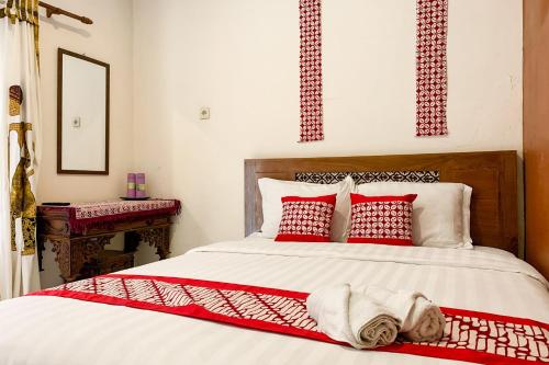 日惹Grha Vege Jawi Syariah Mitra RedDoorz的一间卧室配有红色和白色枕头的床