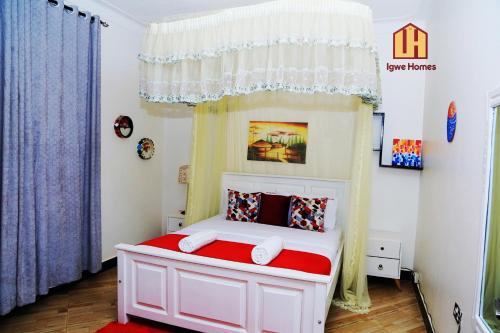 坎帕拉Igwe Homes - Kisaasi的一间小卧室,配有一张白色的床和红色毯子