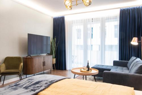 布达佩斯Grand Suites Corvin的客厅配有床、电视和沙发。