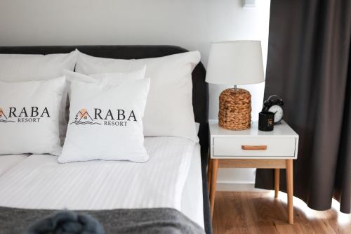 GdówRABA RESORT - Domki i Apartamenty pod Krakowem的一张带白色枕头的床和一张带台灯的边桌