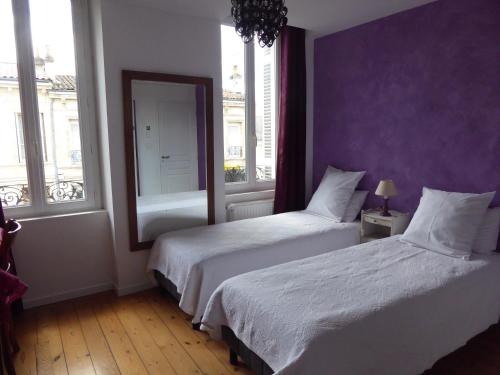 波尔多拉梅森城堡庄园住宿加早餐酒店的卧室设有两张床,拥有紫色的墙壁和窗户。