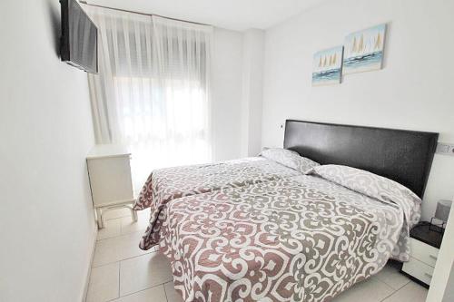 瓜尔达马尔·德尔·塞古拉Apartamento 10 Marjal Playa Centro de Guardamar的一间卧室配有一张带被子的床和一台电视机