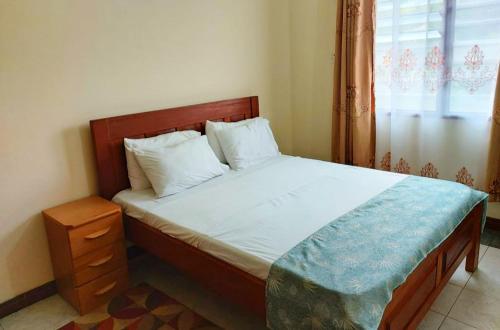 蒙巴萨Sandy Luxury Home, Nyali的一间卧室配有一张带木制床头板的床和窗户。