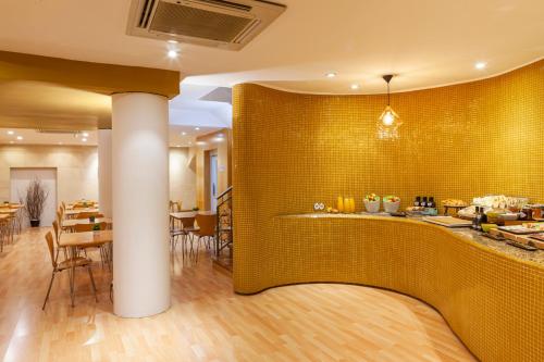 格拉纳达Hotel Macià Plaza的餐厅设有黄色的瓷砖墙和桌子