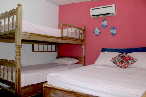 拉利伯塔德Kali Hostal的粉红色墙壁的客房内设有两张双层床。