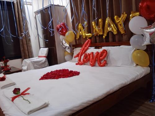 KoynanagarVinee's Kitchen and Motel的一张带气球的床和一个表示幸福爱的标志