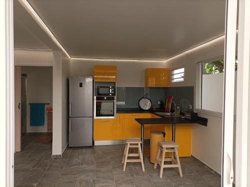 莱昂斯-达赫雷Lez'arlet Plage的厨房配有黄色橱柜和带凳子的柜台。